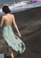 A woman walking on a beach near the ocean.