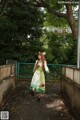 A woman in a green and white dress is walking down a path.