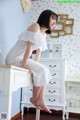 A woman sitting on top of a white dresser.