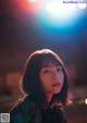 A woman standing in front of a street light at night.