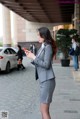 A woman in a gray suit is looking at her phone.