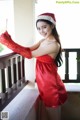 A woman in a red dress and a santa hat posing for a picture.