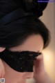 A woman wearing a black lace eye mask with a bow.