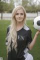 A young woman holding a soccer ball on a field.