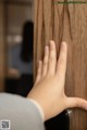 A person's hand is touching a wooden door.