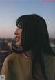 A woman with long black hair smiles at the sky.