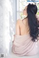 A woman sitting on a window sill looking out the window.