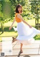 A woman in a white skirt is dancing on a wooden deck.