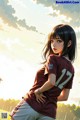 A girl in a maroon shirt is standing on a soccer field.