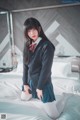 A woman in a school uniform sitting on a bed.