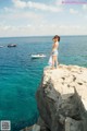 A woman standing on the edge of a cliff overlooking the ocean.