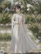 A woman in a white kimono standing in a park.