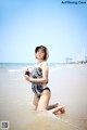 A woman in a black and white bathing suit on the beach.