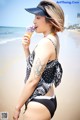 A woman in a bikini eating an ice cream cone on the beach.