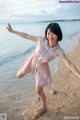 A woman in a pink dress standing on a beach.