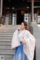 A woman in a blue and white hanbok standing on some steps.